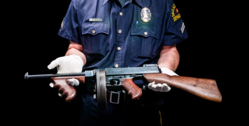 The curator of the Dallas Police Museum displays a vintage shotgun: Photo by Danny Fulgencio