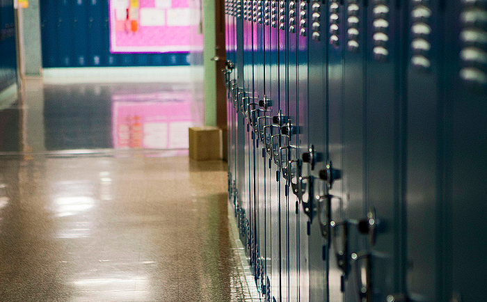 A set of lockers in a high school hallway. All of the lockers are locked and closed.