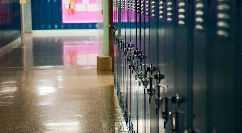 A set of lockers in a high school hallway. All of the lockers are locked and closed.