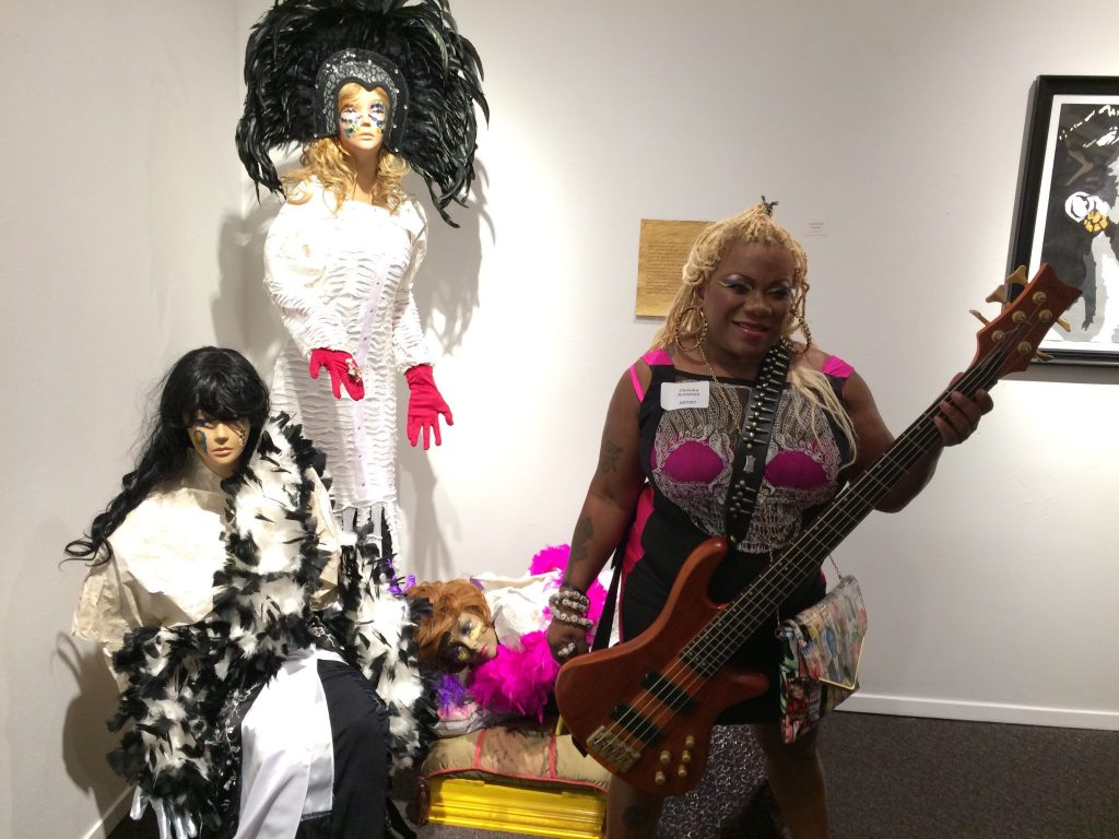 Arlington artist Chandra Armstead poses in front of her creation, “Paper Dolls.” Armstead has contributed to the exhibition for nine years. She volunteers with youth in her community, works at TI, and is also a weight lifter in addition to her creative endeavors.