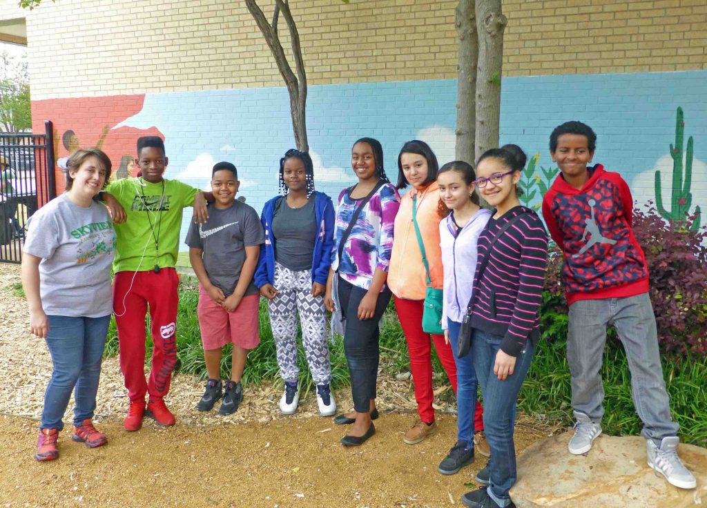 Art teacher Emily Ash (left) with sixth graders who helped paint the mural behind them