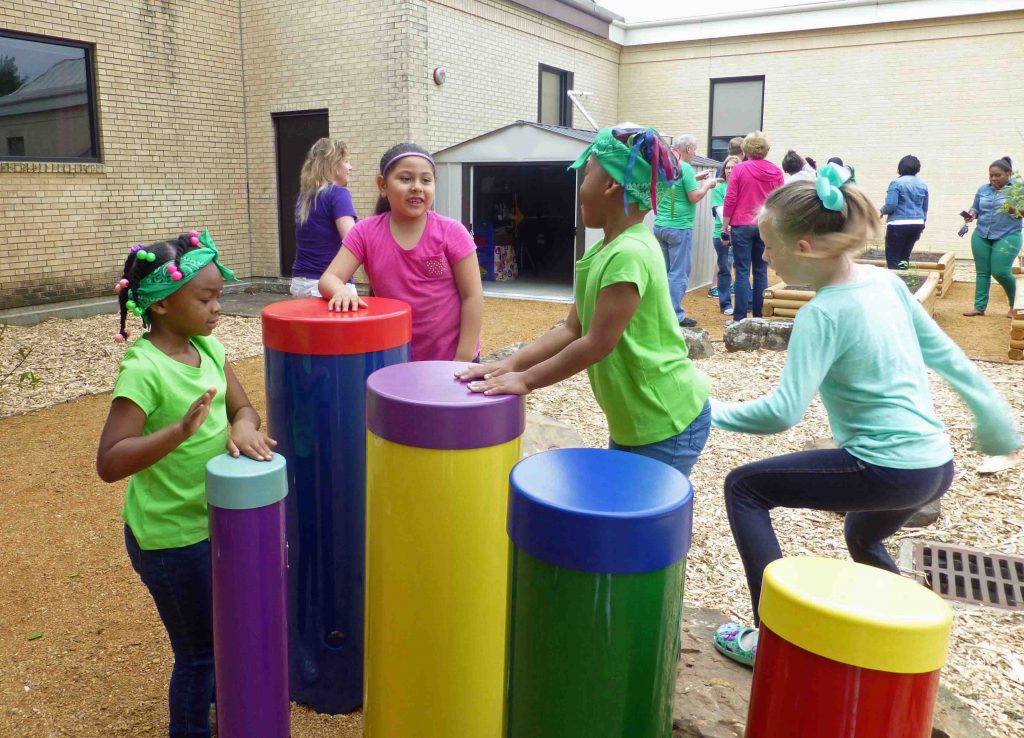 Children play on the Tubano drum set in Skyview's new Harmony Garden