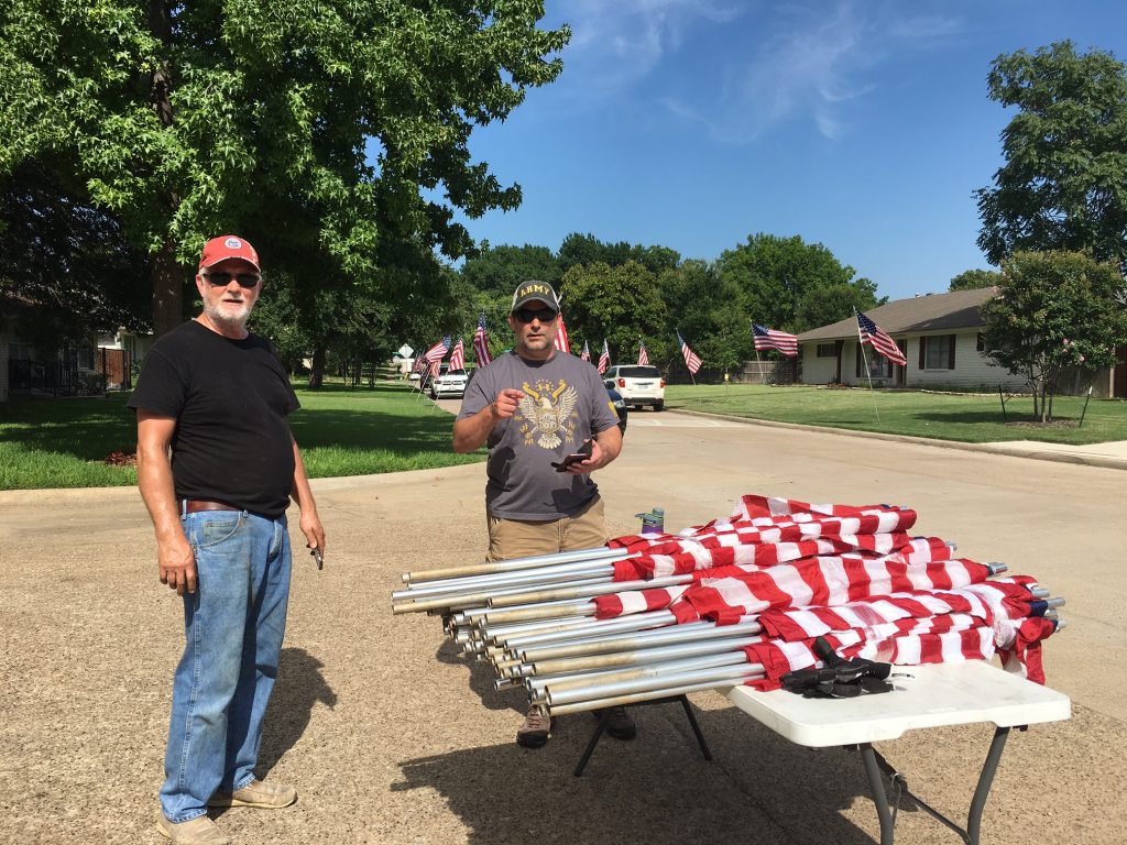 Jerry Reddy and Fred Schmelling prepare American flags for display.