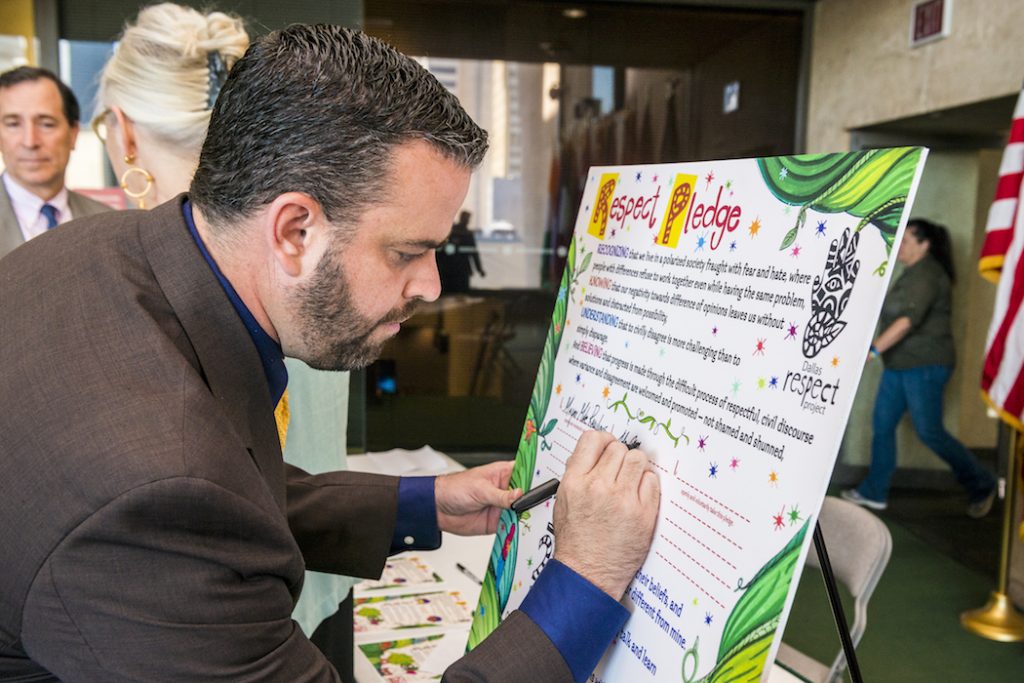 Councilman Adam McGough signs a "Respect Pledge" during the June kickoff event for the 2016 Dallas Peace Day. Dallas artist and community activist, Karen Blessen, along with young people from 29 Pieces, an inner city arts arts initiative, asked the willing to sign the pledge, committing to respect and peace when beset by adversity. (Photo by Danny Fulgencio)