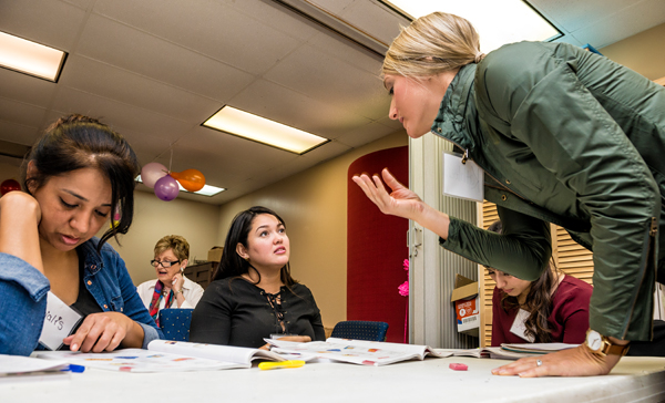 Alejandra Valbuena, middle, and other students learn English from volunteers at Pamper Lake Highlands, a nonprofit benefitting local women and children. She takes adult literacy classes three days a week and recently began working at the charity’s childcare center. Photo by Danny Fulgencio
