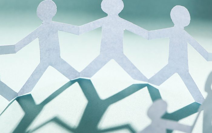 Group of people made of paper are holding hands together.