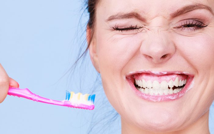 Woman brushing cleaning teeth. Girl with toothbrush. Oral hygiene. Blue background