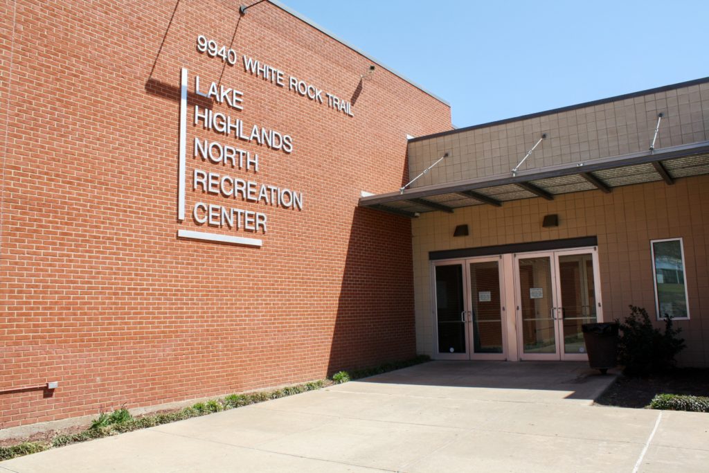 A set of doors leading into a brick building. The sign next to the doors says "Lake Highlands North Recreation Center."